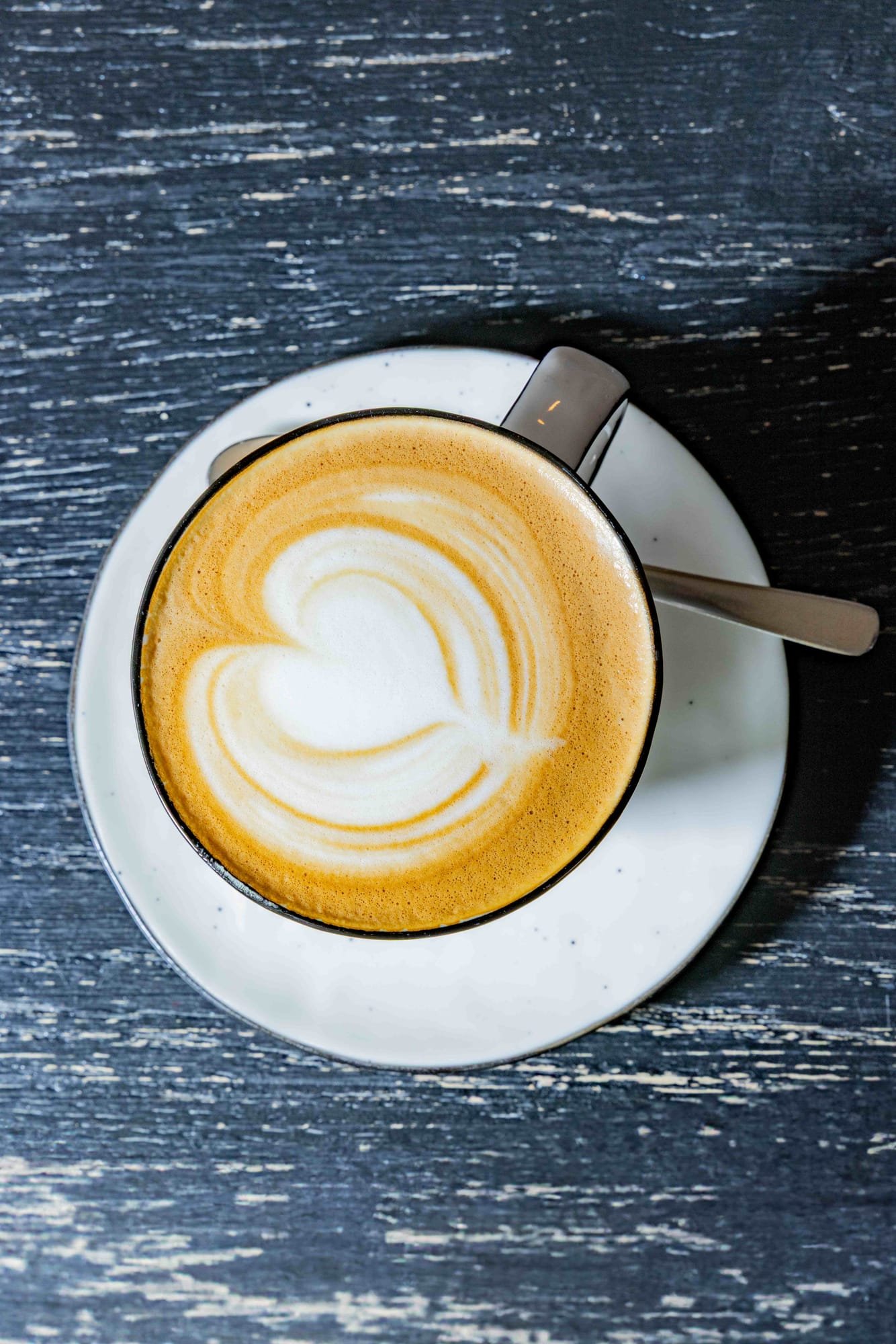 Cappuccino mit Herz-Latte-Art von oben auf dunklem Holz