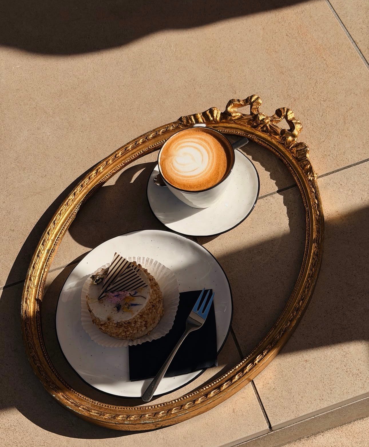 Cappuccino und Kuchen auf einem goldenen Spiegeltablett