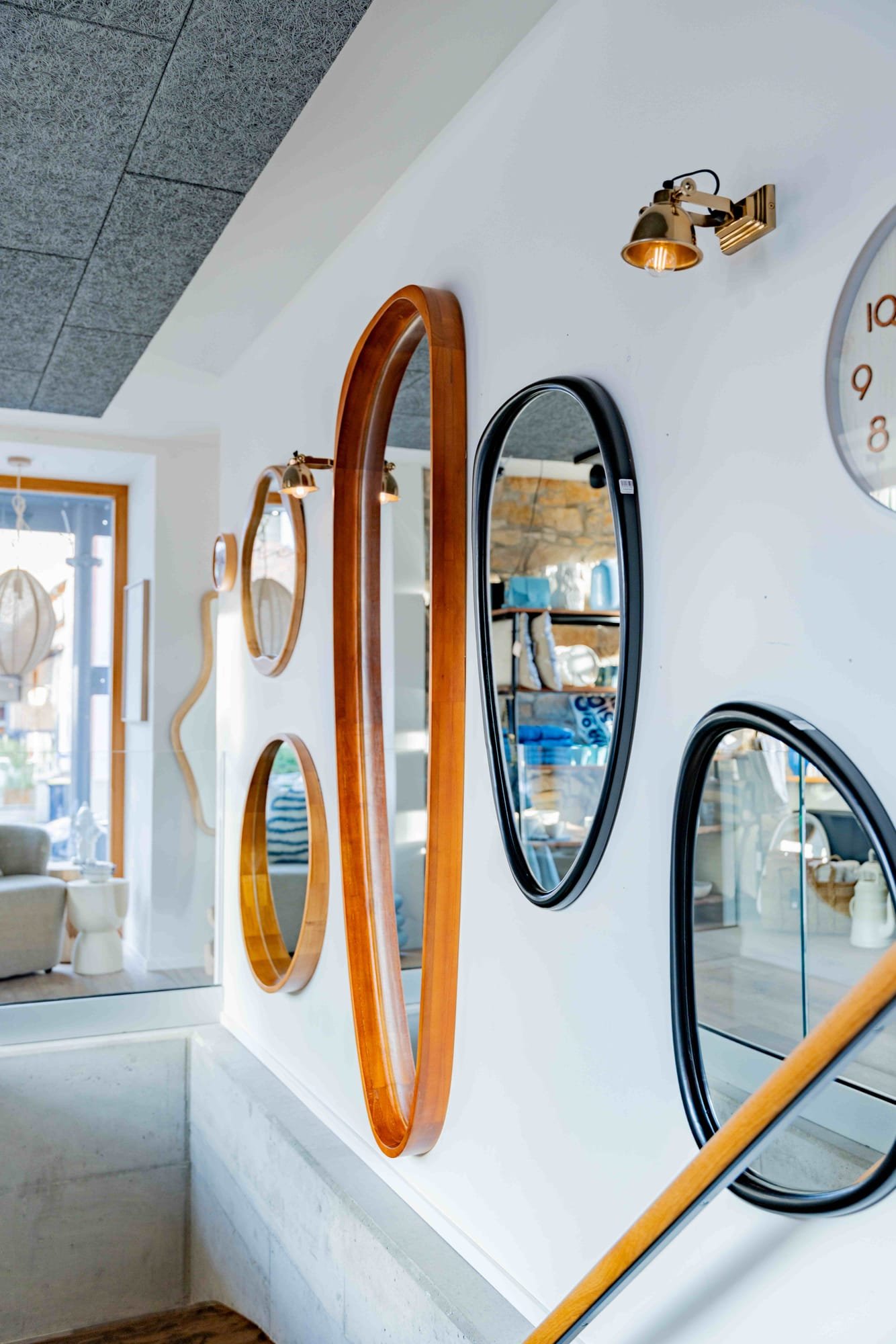 Wand mit kuratierten Designer-Spiegeln und Messingleuchten im Kamé Showroom